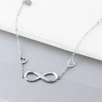a silver necklace with a heart and an infinite symbol on it