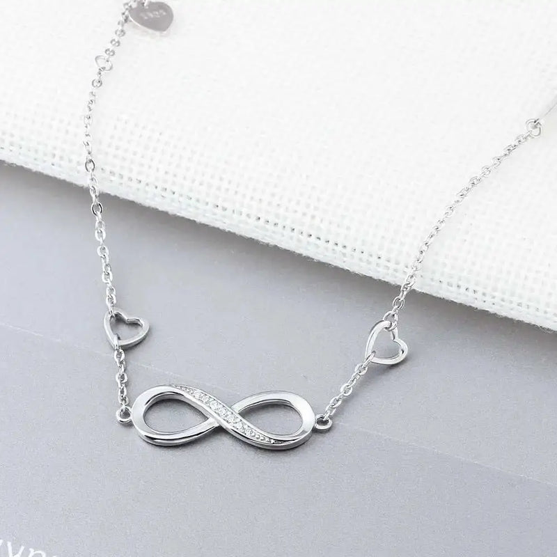 a silver necklace with a heart and an infinite symbol on it