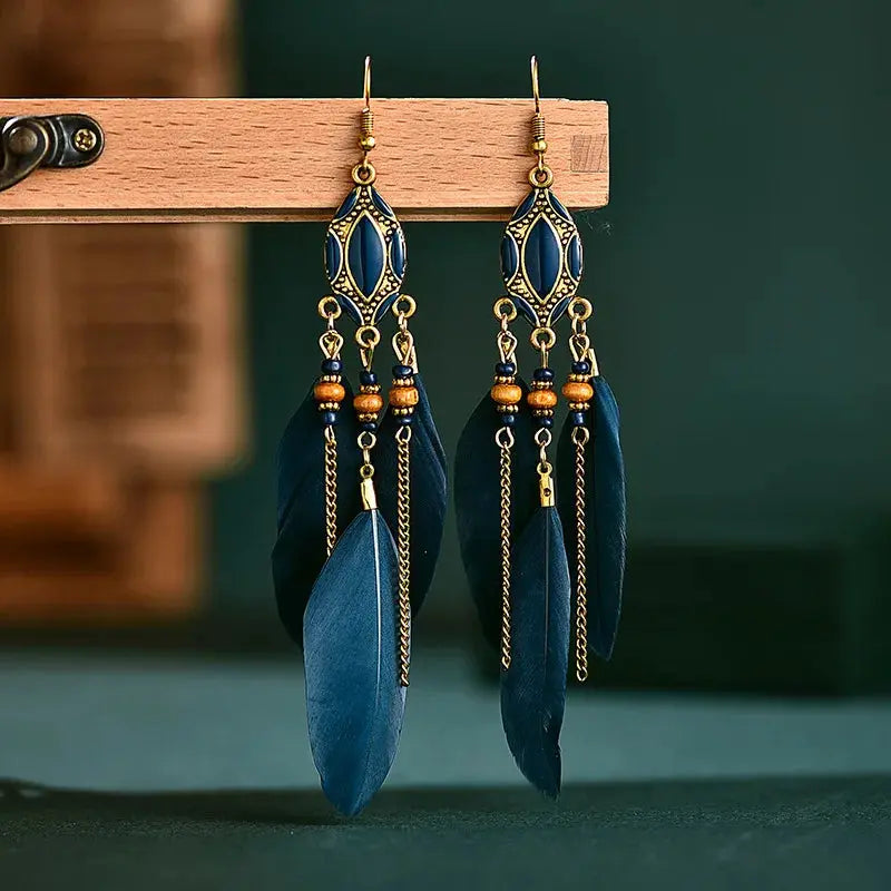 a pair of blue feather earrings hanging from a hook