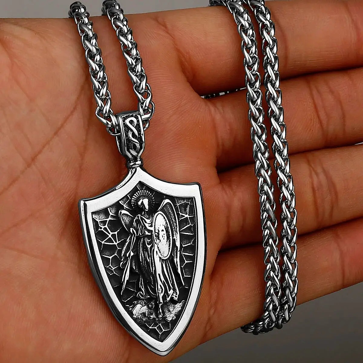 a hand holding a silver chain with a pendant on it