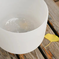 a white singing bowl filled with water sitting on top of a wooden table