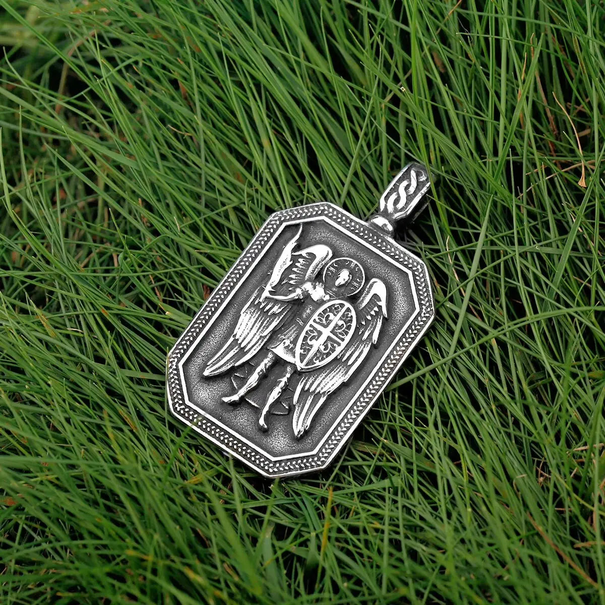 a silver pendant with a picture of a bird on it