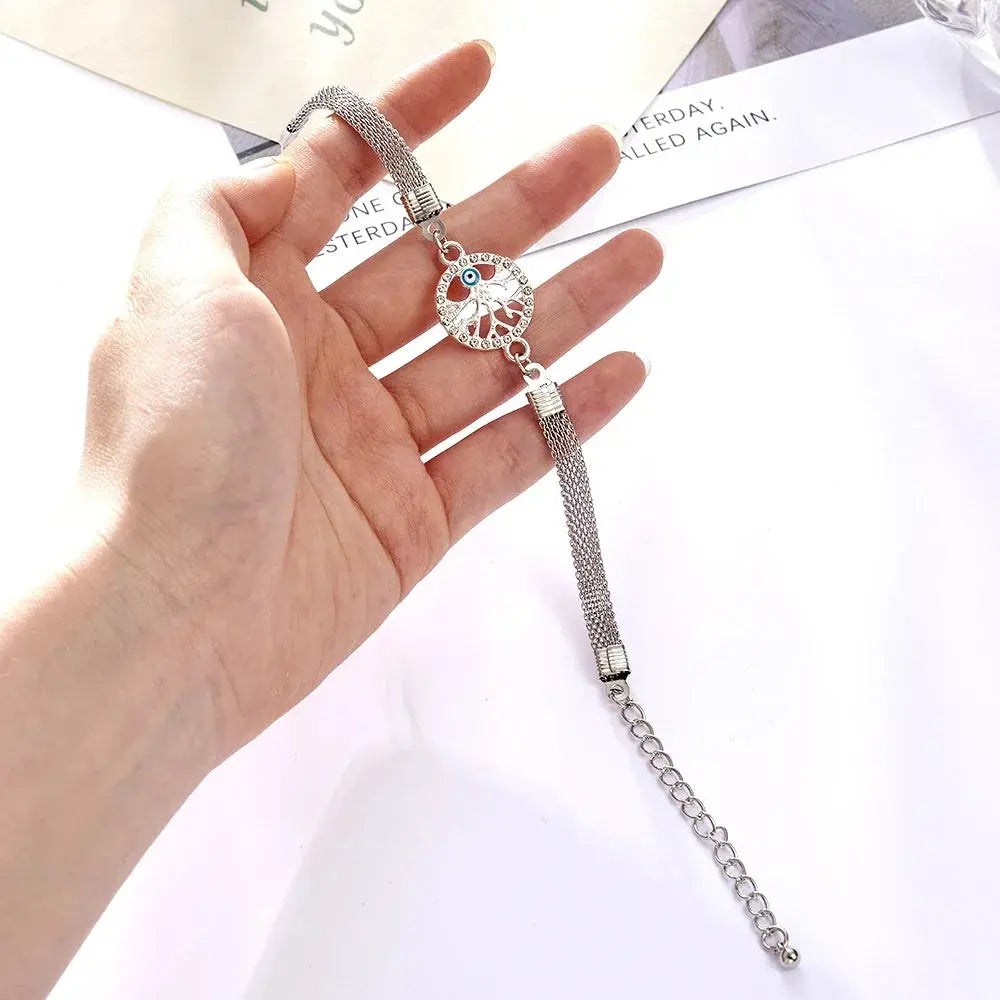 woman holding a rhinestone bracelet with tree of life charm on it