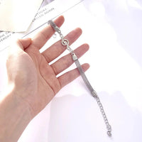 hand holding a silver bracelet with a rhinestone musical note charm on it