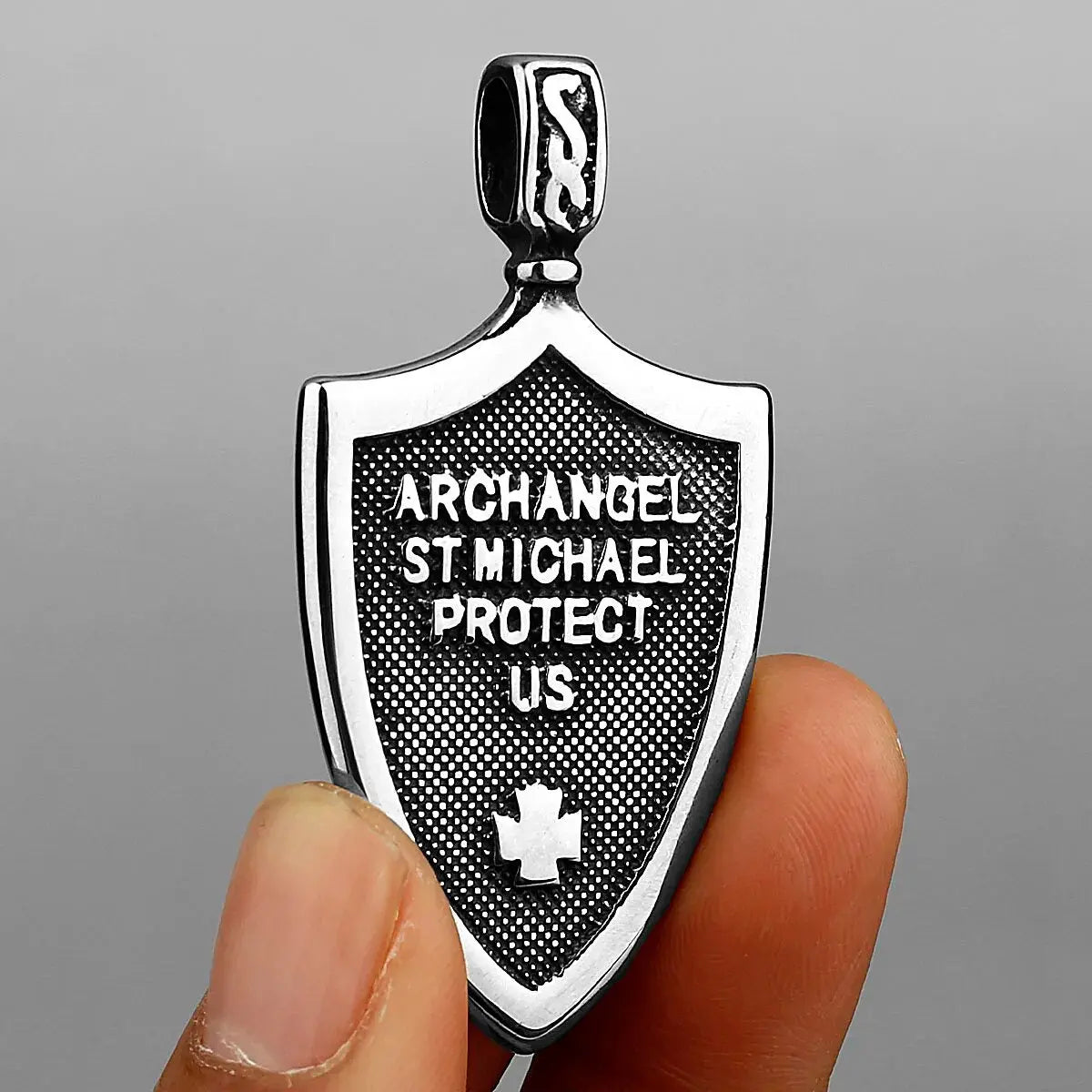 a person holding a small metal badge with a cross on it