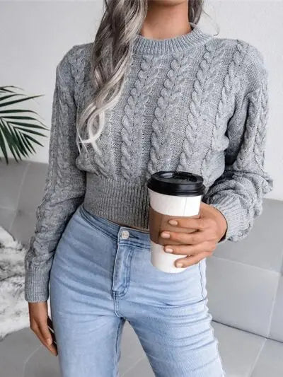 a woman wearing a gray sweater and jeans holding a cup of coffee