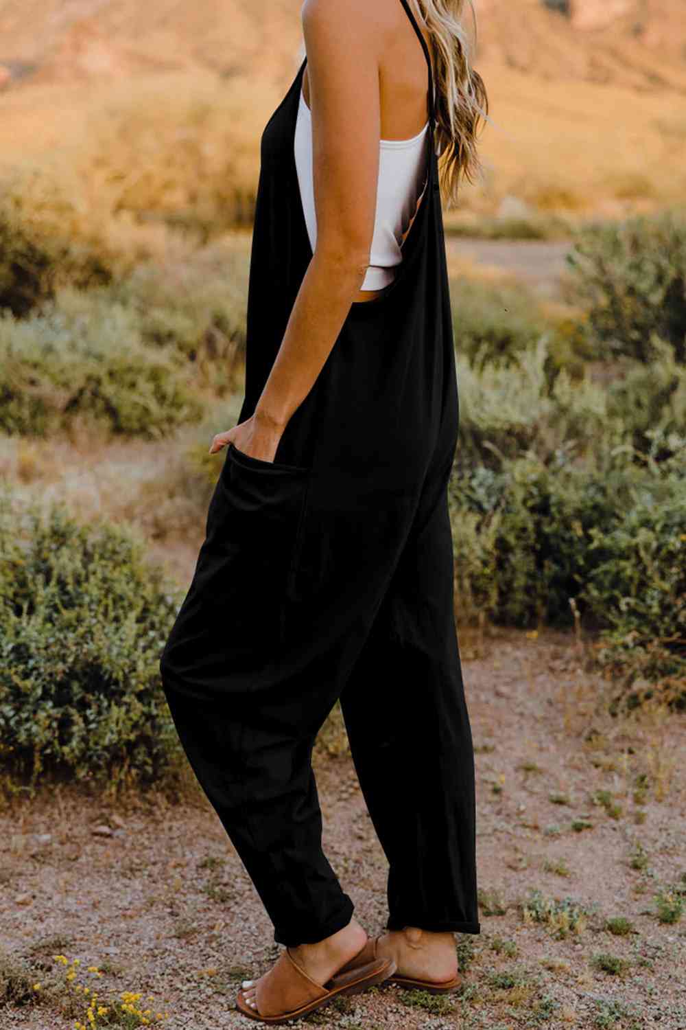 a woman standing in a field wearing a black jumpsuit