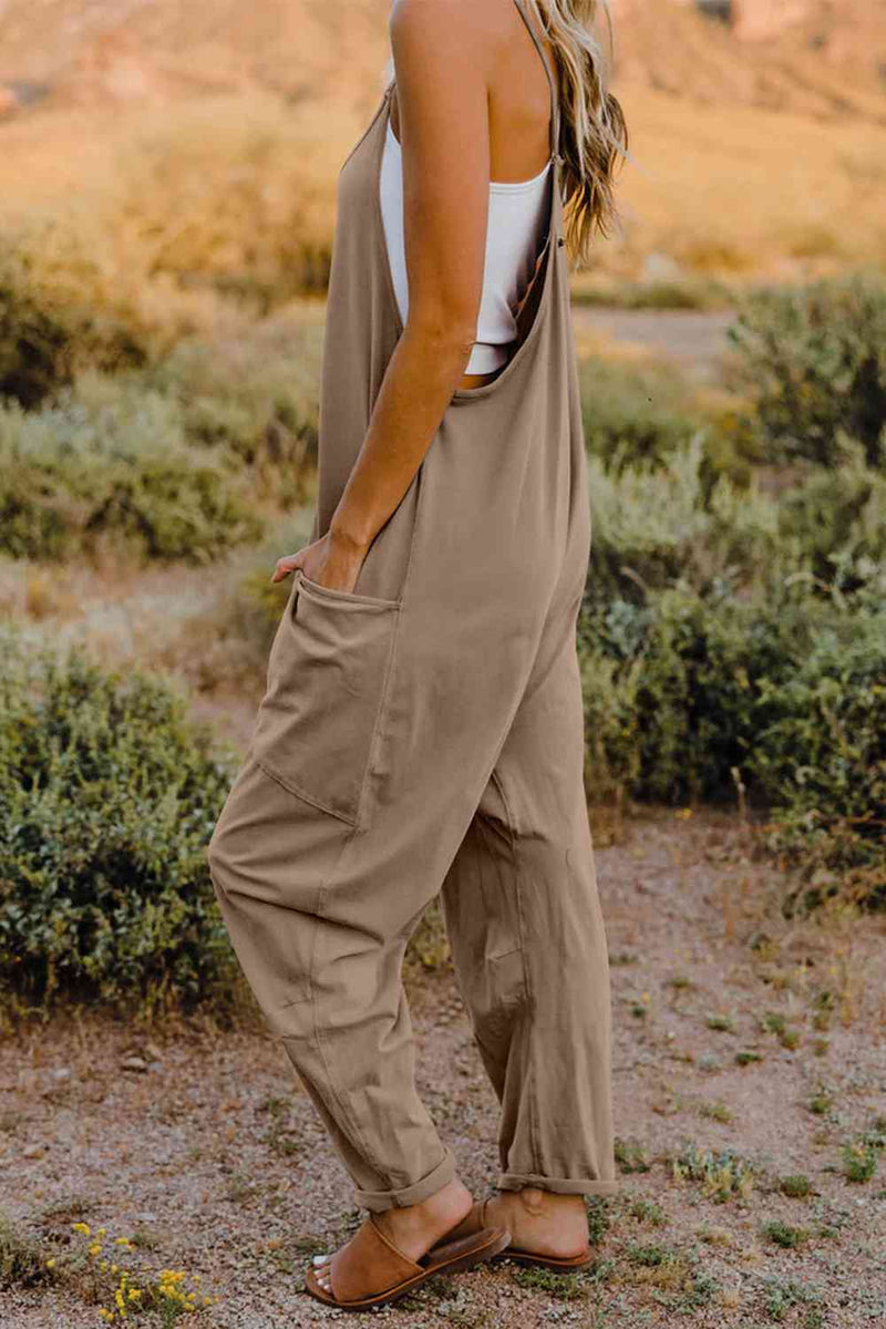 a woman standing in a field wearing a tan jumpsuit