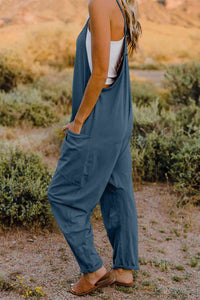 a woman standing in a field wearing a blue jumpsuit