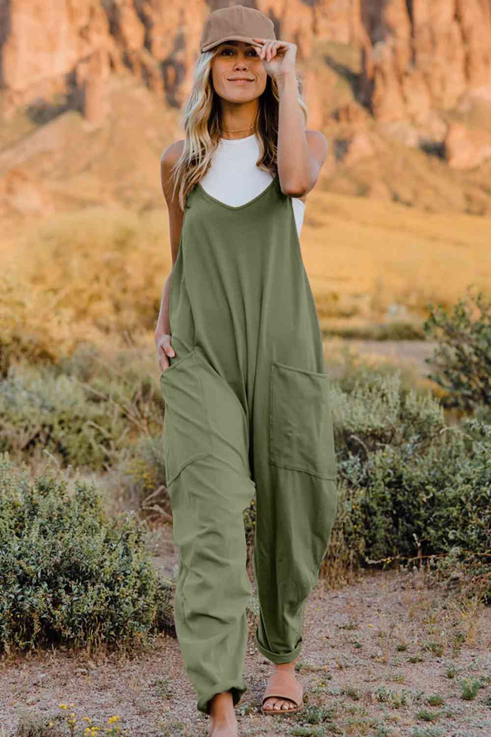 a woman wearing a green jumpsuit and a hat