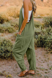 a woman standing in a field wearing a green jumpsuit